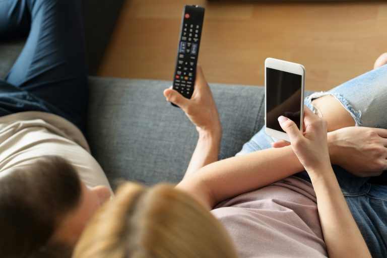 Streaming e redes sociais começam a se tornar uma coisa só. Imagem de pessoas com celular e controle da TV na mão.
